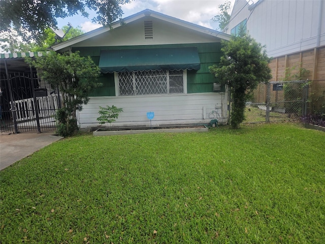 view of front of home featuring fence, a gate, and a front lawn