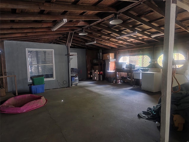 misc room featuring washer / dryer, a garage, unfinished concrete floors, and lofted ceiling