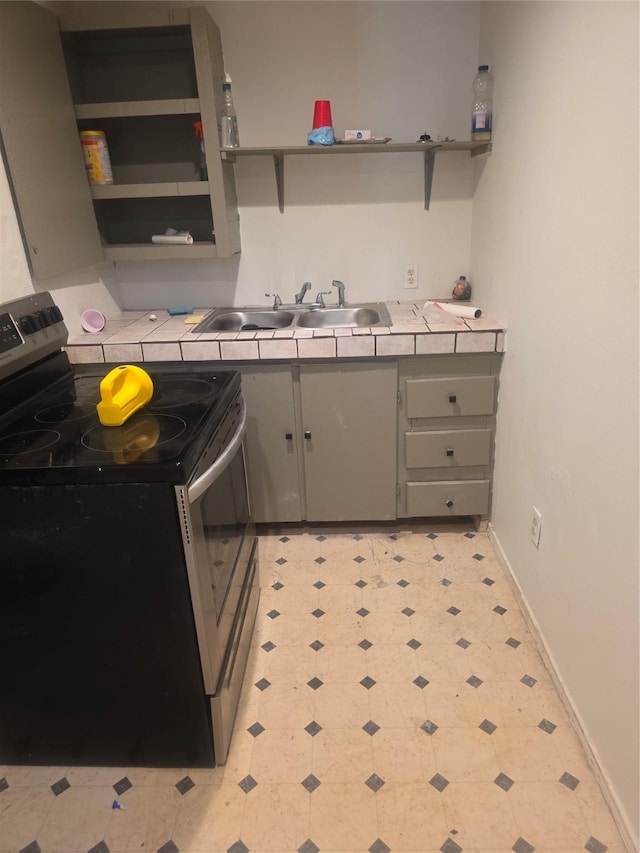 kitchen featuring a sink, stainless steel electric range oven, gray cabinets, and open shelves