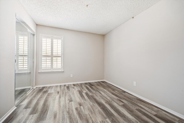 unfurnished room with baseboards, a textured ceiling, and wood finished floors