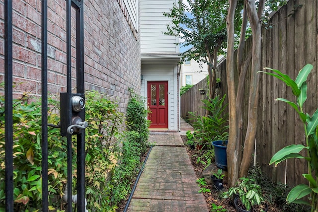 entrance to property featuring brick siding and fence