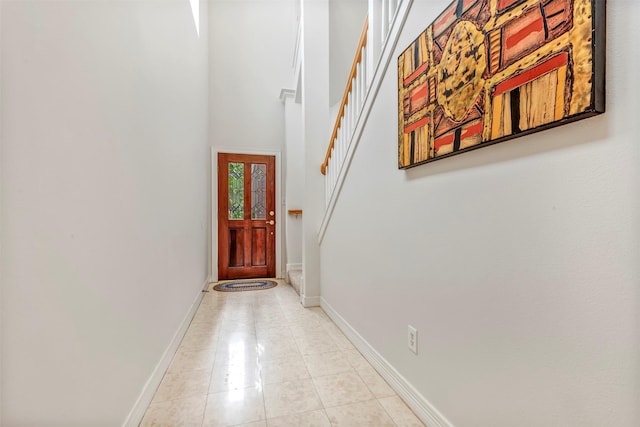 doorway to outside featuring light tile patterned floors, a high ceiling, baseboards, and stairway