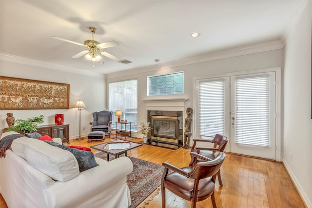living area with visible vents, a ceiling fan, a premium fireplace, and ornamental molding