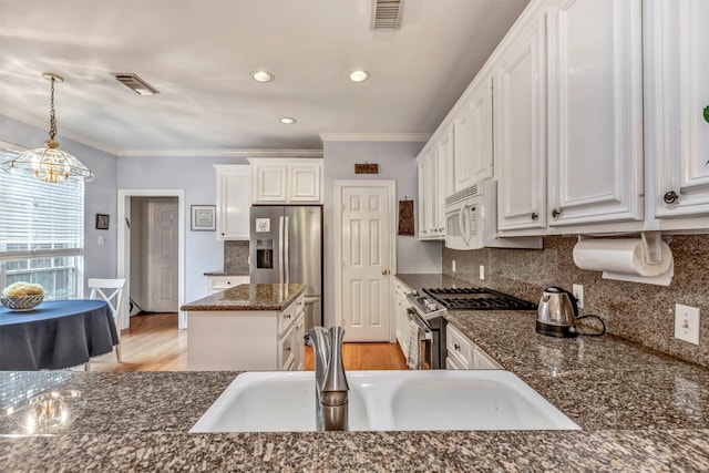 1202 Joe Annie St, Houston, TX 77019 - kitchen with appliances with stainless steel finishes, ornamental molding, white cabinets, and visible vents