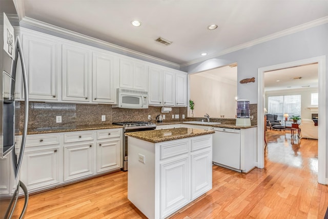 kitchen with appliances with stainless steel finishes, a sink, a center island, white cabinetry, and visible vents