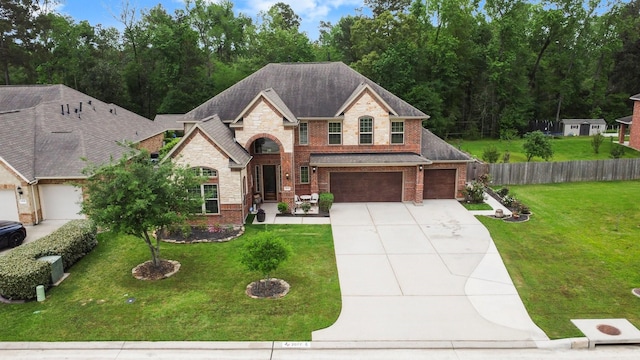 view of front of home featuring driveway, brick siding, fence, a front lawn, and stone siding