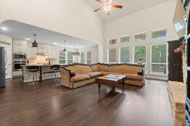 living room featuring ceiling fan, dark wood-style floors, and high vaulted ceiling