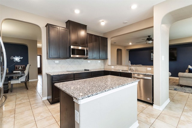 kitchen with ceiling fan, appliances with stainless steel finishes, a sink, arched walkways, and light tile patterned floors
