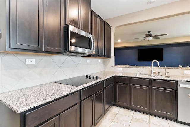 kitchen with dark brown cabinets, ceiling fan, a sink, stainless steel appliances, and decorative backsplash