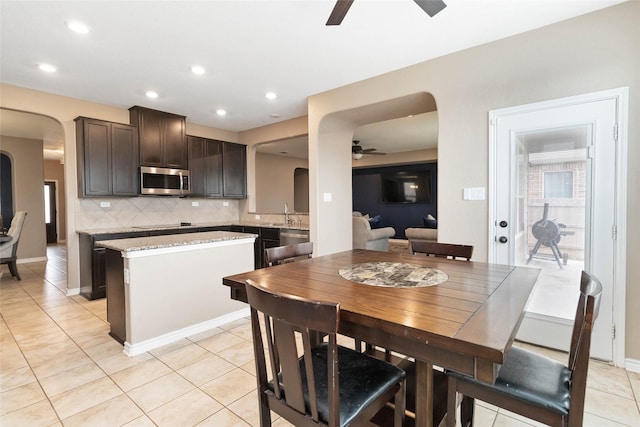 kitchen with arched walkways, ceiling fan, appliances with stainless steel finishes, and decorative backsplash