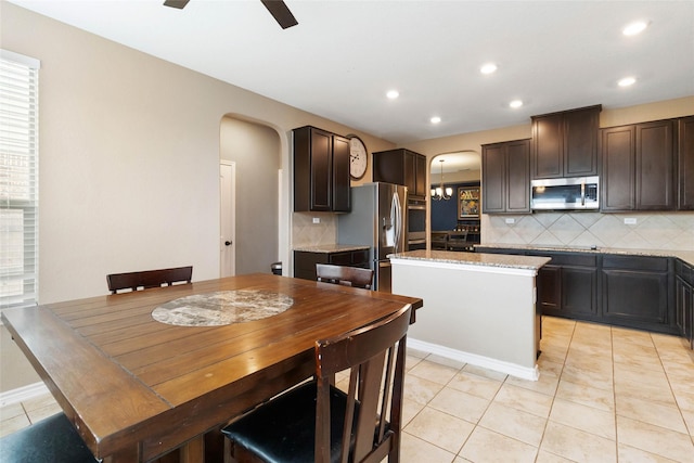 kitchen with arched walkways, backsplash, appliances with stainless steel finishes, and dark brown cabinets