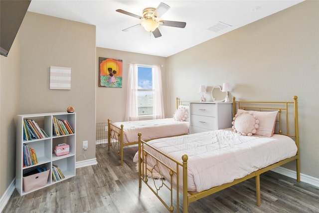 bedroom with baseboards, a ceiling fan, wood finished floors, and visible vents