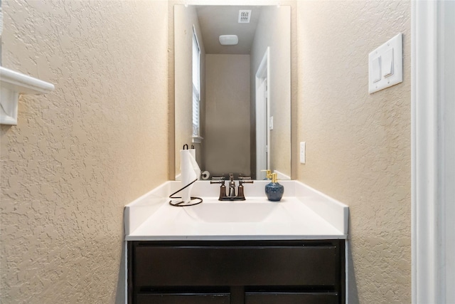 bathroom with a textured wall and vanity