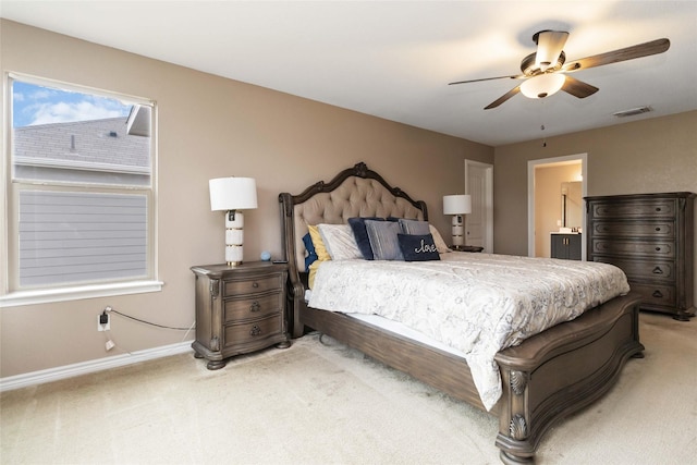 bedroom featuring visible vents, baseboards, ensuite bathroom, light colored carpet, and a ceiling fan