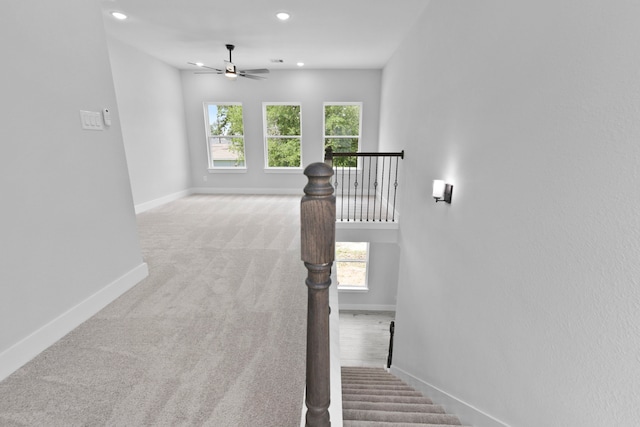 staircase with baseboards, plenty of natural light, a ceiling fan, and carpet flooring