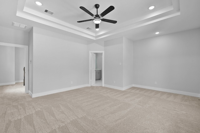 spare room featuring ceiling fan, light carpet, a raised ceiling, recessed lighting, and visible vents