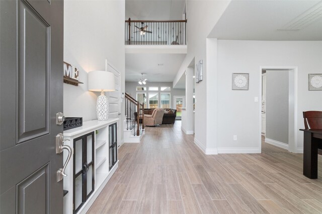 foyer featuring light wood-style floors, ceiling fan, and stairs