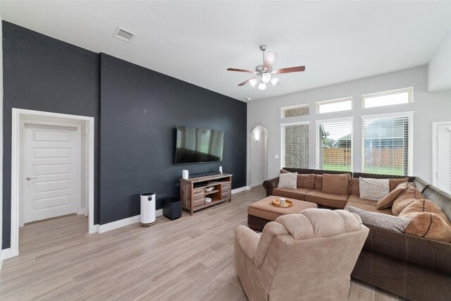 living room with ceiling fan, visible vents, baseboards, and light wood-style floors