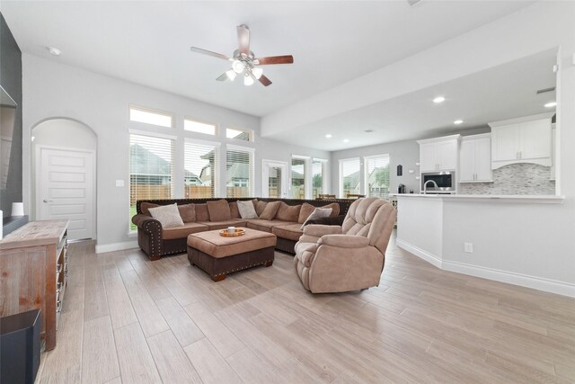 living room with baseboards, recessed lighting, ceiling fan, and light wood-style flooring