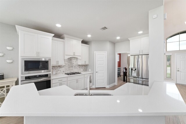 kitchen with stainless steel appliances, visible vents, a sink, and light wood-type flooring