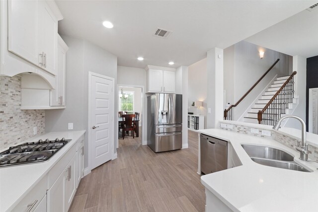 kitchen with visible vents, appliances with stainless steel finishes, a sink, white cabinets, and light wood-style flooring