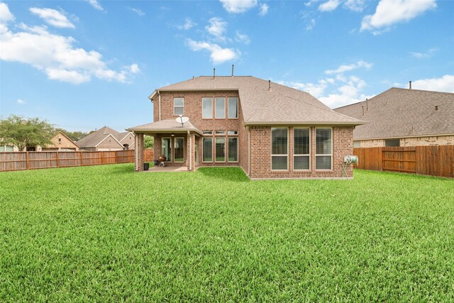 back of property with brick siding, a fenced backyard, a patio area, and a yard