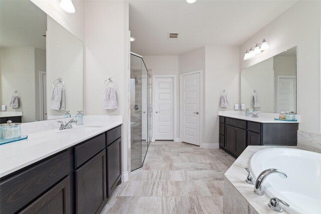 full bathroom featuring a bath, visible vents, a stall shower, two vanities, and a sink