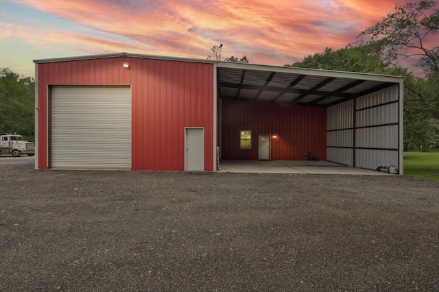 garage at dusk featuring a carport and a detached garage