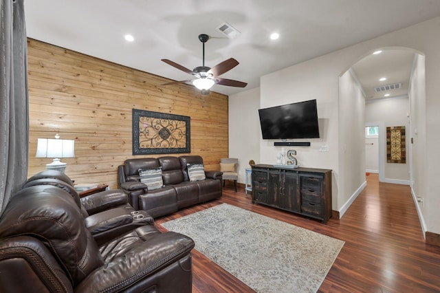 living room with visible vents, arched walkways, ceiling fan, and dark wood-type flooring