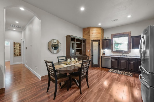 dining area with arched walkways, wood finished floors, and visible vents