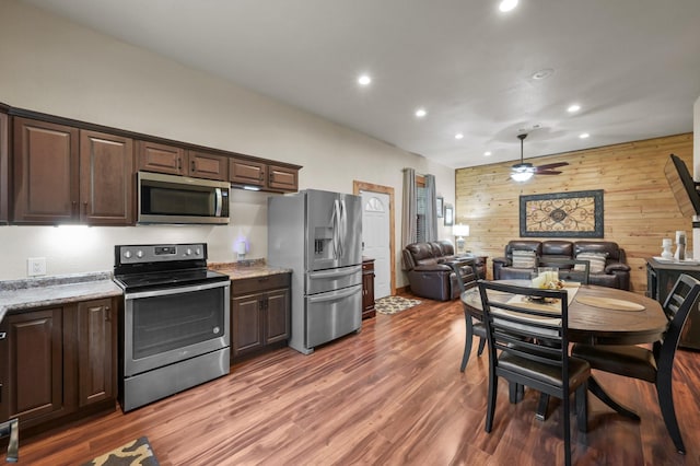 kitchen with wood walls, dark brown cabinets, open floor plan, recessed lighting, and appliances with stainless steel finishes