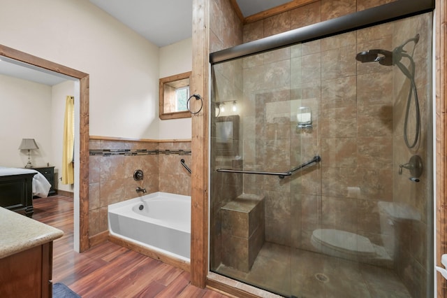 bathroom featuring vanity, a bath, wood finished floors, and a shower stall