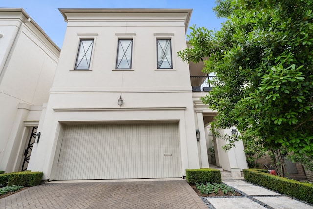view of front property with stucco siding, decorative driveway, and a garage