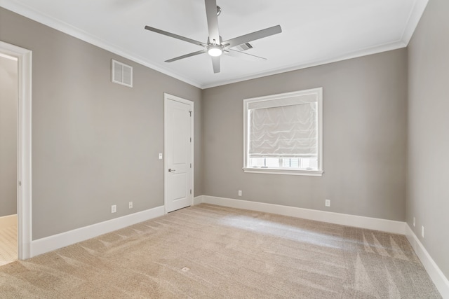 spare room featuring light carpet, a ceiling fan, baseboards, visible vents, and ornamental molding
