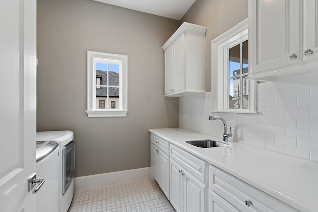 washroom with cabinet space, a sink, baseboards, light tile patterned floors, and washer and clothes dryer
