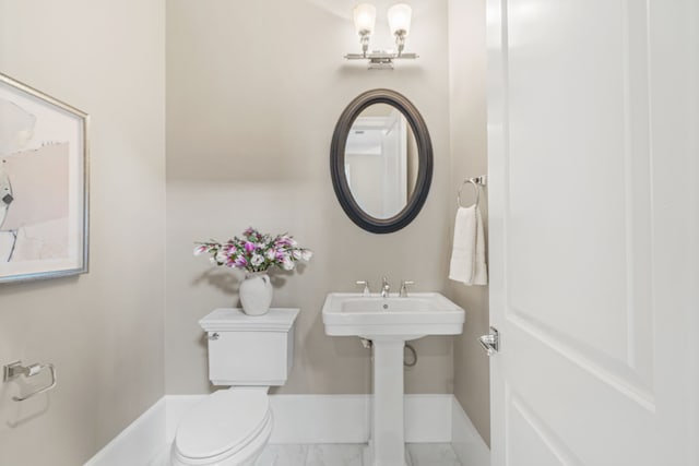 bathroom with toilet, baseboards, and marble finish floor