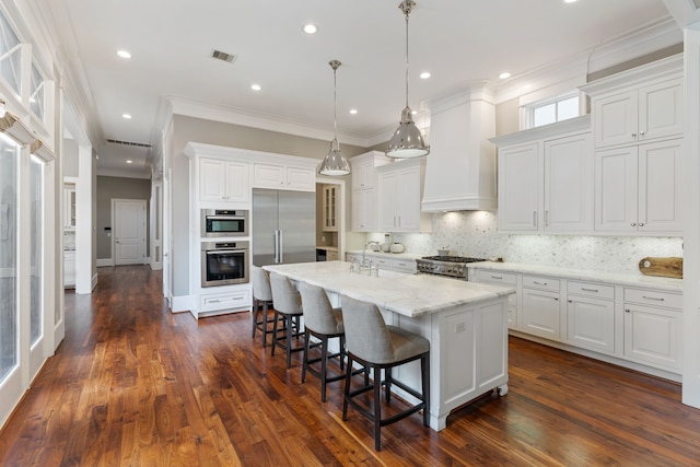 kitchen with visible vents, crown molding, a breakfast bar, an island with sink, and stainless steel appliances
