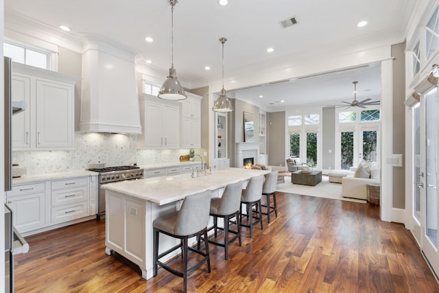 kitchen featuring ceiling fan, high end stainless steel range, a lit fireplace, and a healthy amount of sunlight