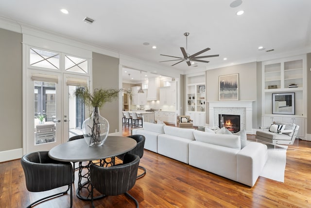 living room with crown molding, recessed lighting, a glass covered fireplace, and ceiling fan