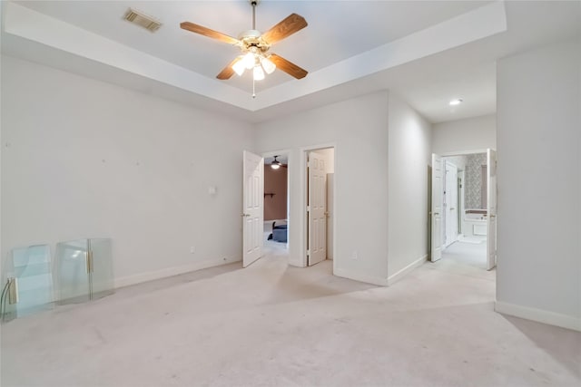 carpeted empty room with a ceiling fan, baseboards, and a raised ceiling