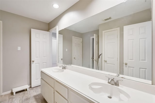 bathroom featuring baseboards and double vanity