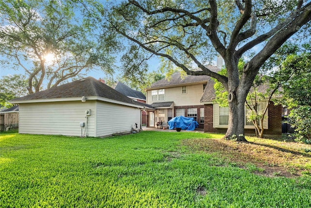rear view of house with a lawn and brick siding