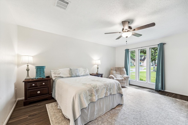 bedroom featuring baseboards, ceiling fan, dark wood-style floors, and visible vents