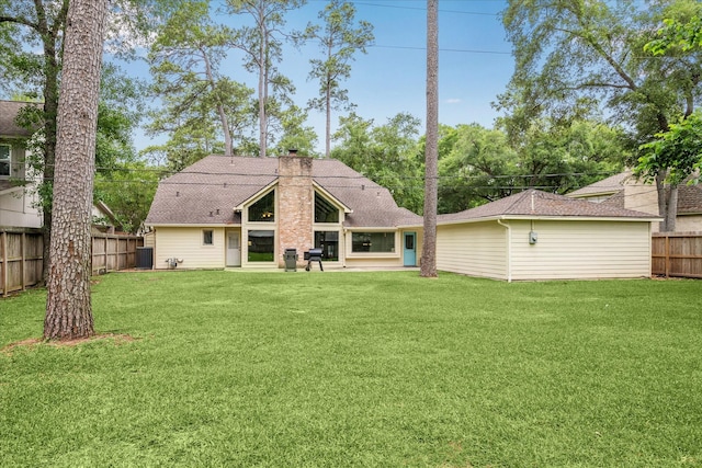 rear view of house featuring fence, a chimney, a lawn, and cooling unit