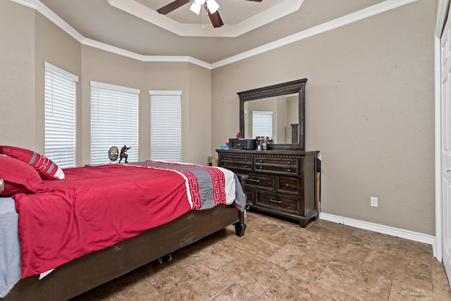 bedroom with baseboards, crown molding, ceiling fan, and a tray ceiling