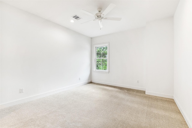 unfurnished room with baseboards, a ceiling fan, light colored carpet, and visible vents
