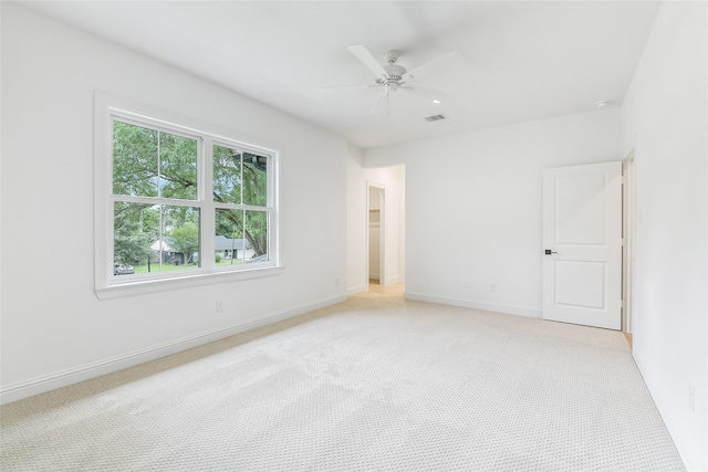 spare room with light colored carpet, baseboards, ceiling fan, and visible vents