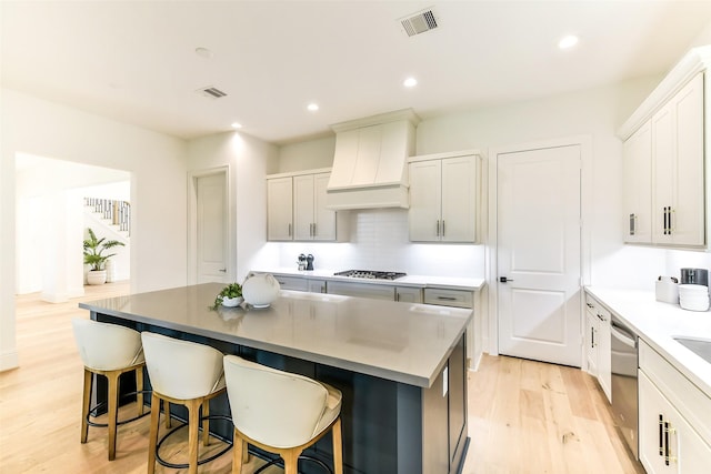 kitchen featuring a center island, visible vents, premium range hood, and light wood-style floors