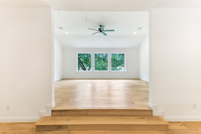spare room with baseboards, a ceiling fan, wood finished floors, and visible vents