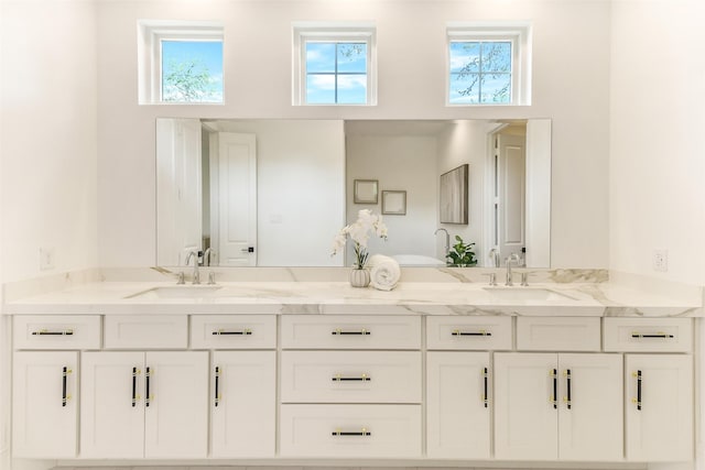 full bath with plenty of natural light, a sink, and double vanity